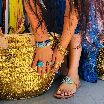Picture of Asa Kaftans products: gold bag, sandal, rings, bracelet, and dress.